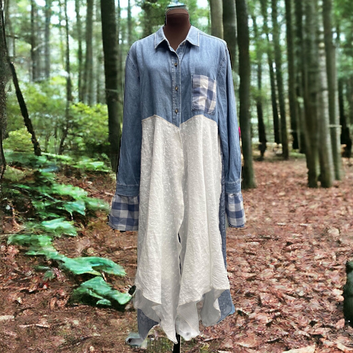 A mannequin wearing a denim shirt in the woods.