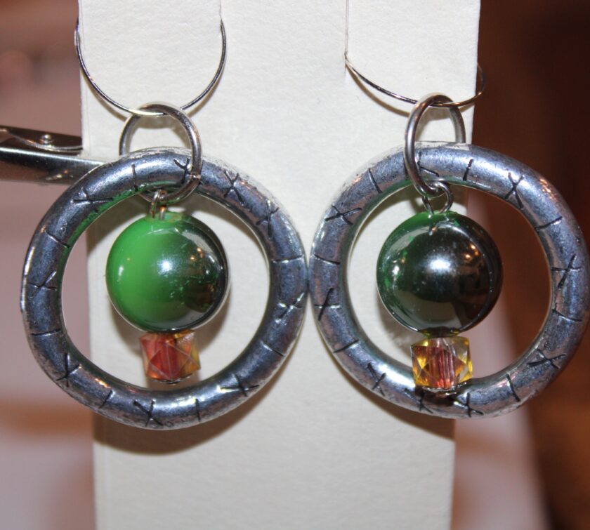 A pair of earrings with a green bead and a silver bead.