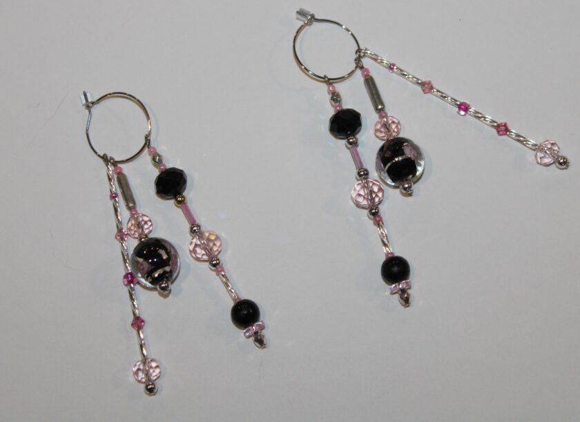 A pair of earrings with black and pink beads.