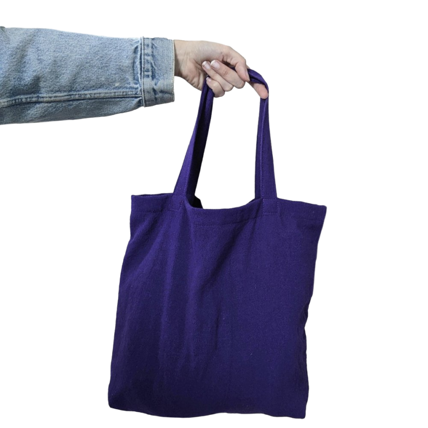 A person holding a purple tote bag on a black background.