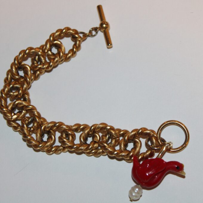 A gold chain bracelet with a red bird and pearl.