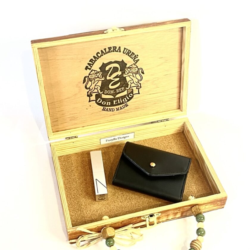 An open wood cigar box purse containing a lipstick and a wallet.