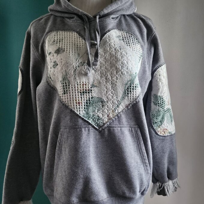 Gray hoodie with lace heart appliqué and patchwork on a mannequin.