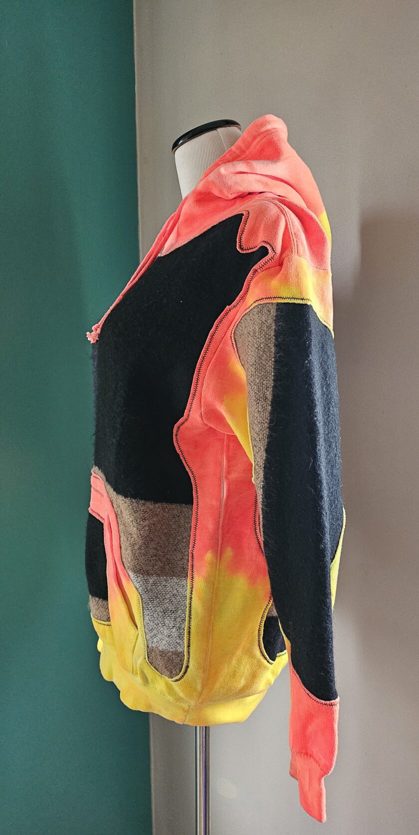 A colorful, patchwork-style hoodie displayed on a mannequin.