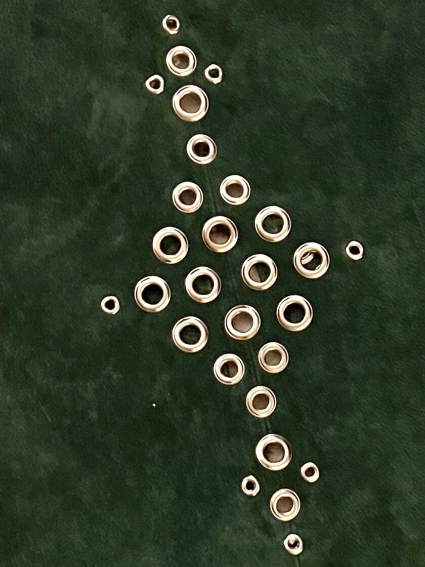 Metal washers arranged on a green surface in a pattern resembling a christmas tree.