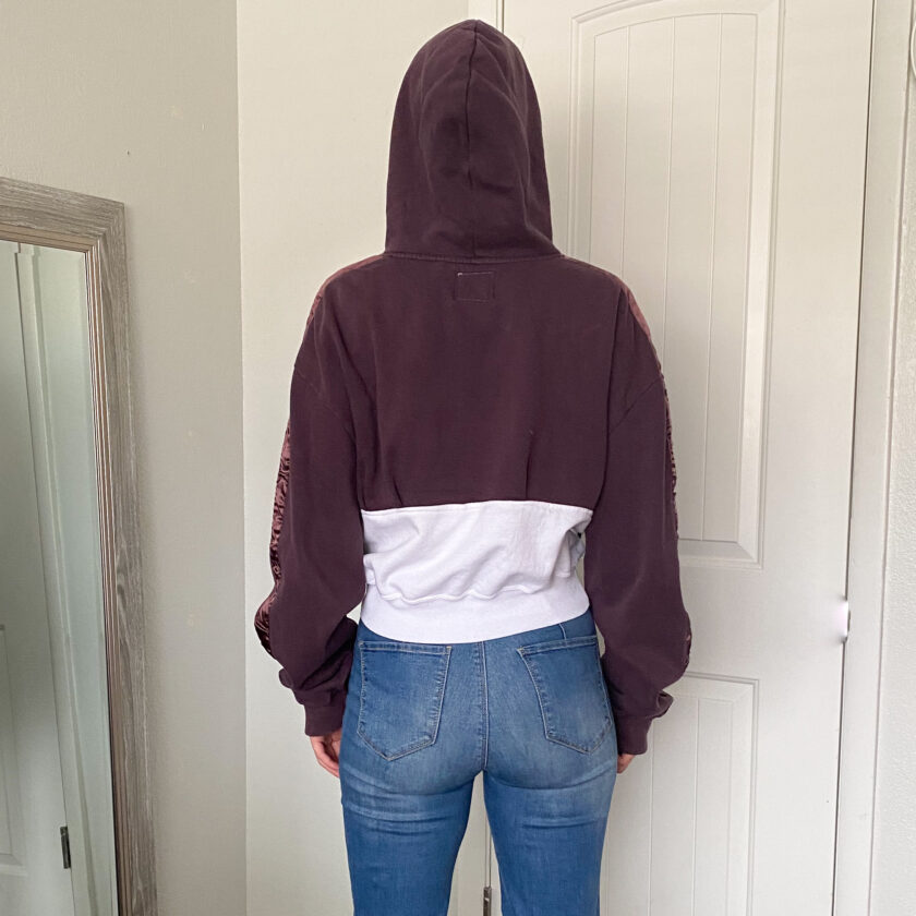 The back of a woman wearing jeans and a hoodie.