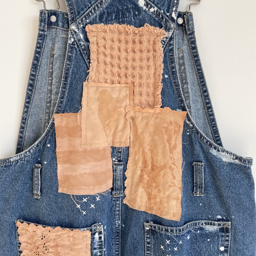A denim overall with patches on it.