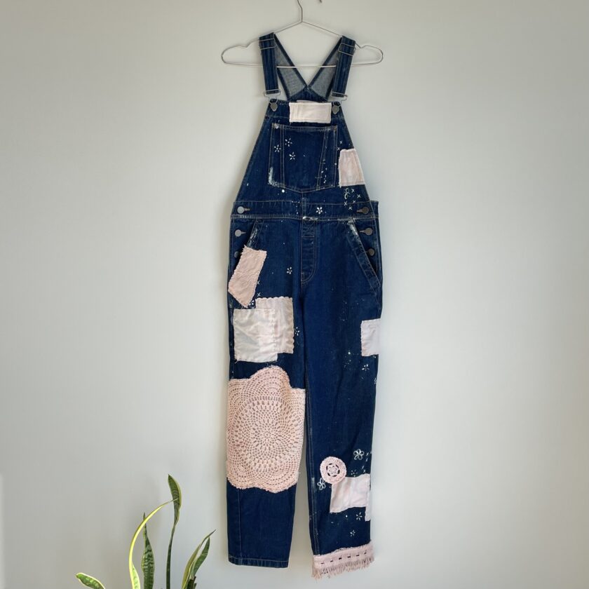 A pair of denim overalls hanging on a wall.