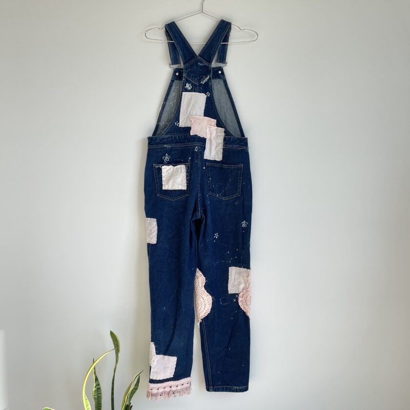 A pair of denim overalls hanging on a wall.