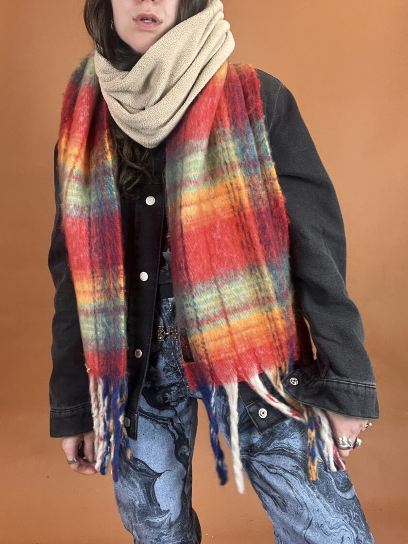 A woman wearing a colorful scarf and jeans.