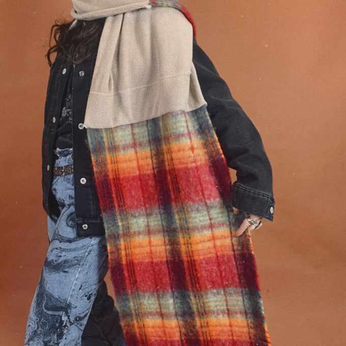 A woman wearing a plaid scarf and jeans.