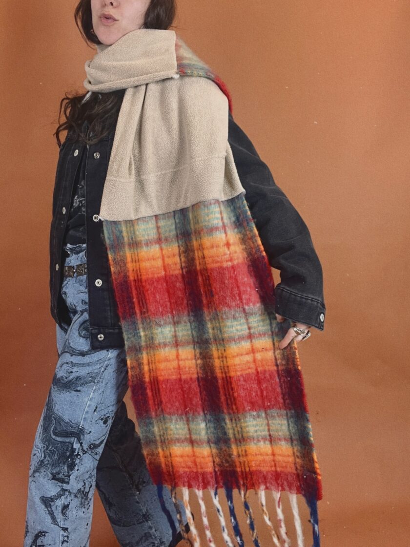 A woman wearing a plaid scarf and jeans.