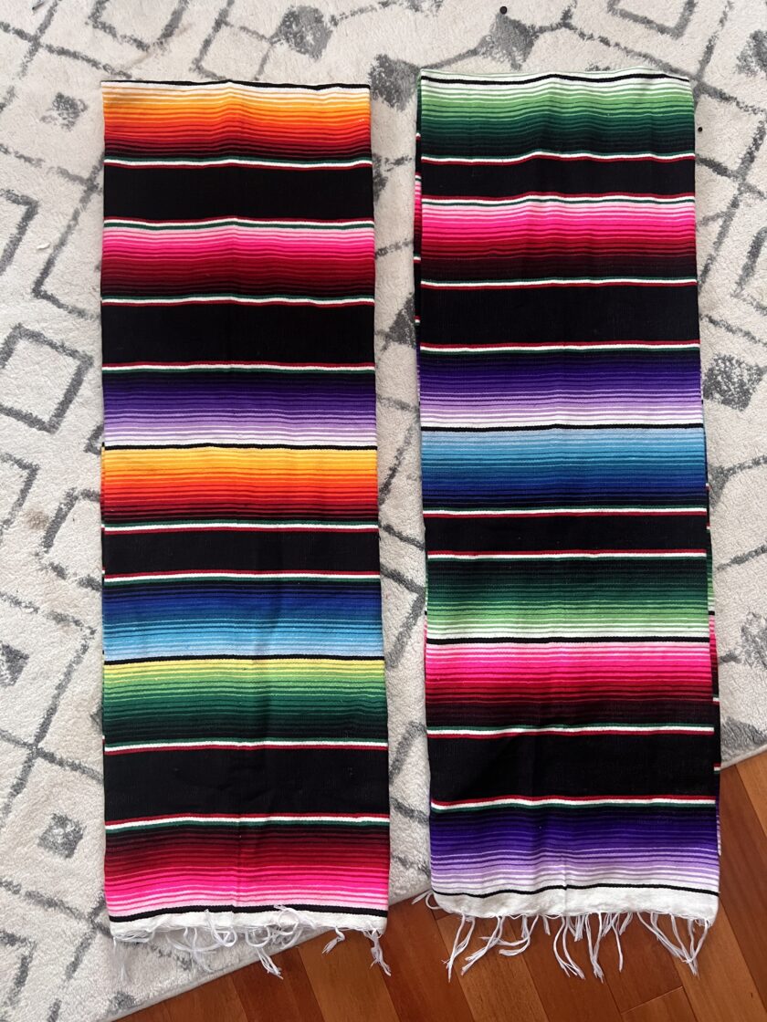 Two colorful mexican blankets on a rug.