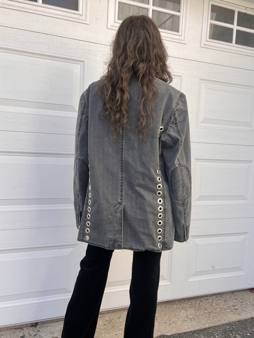 Person standing in front of a garage door wearing a denim jacket and black pants.