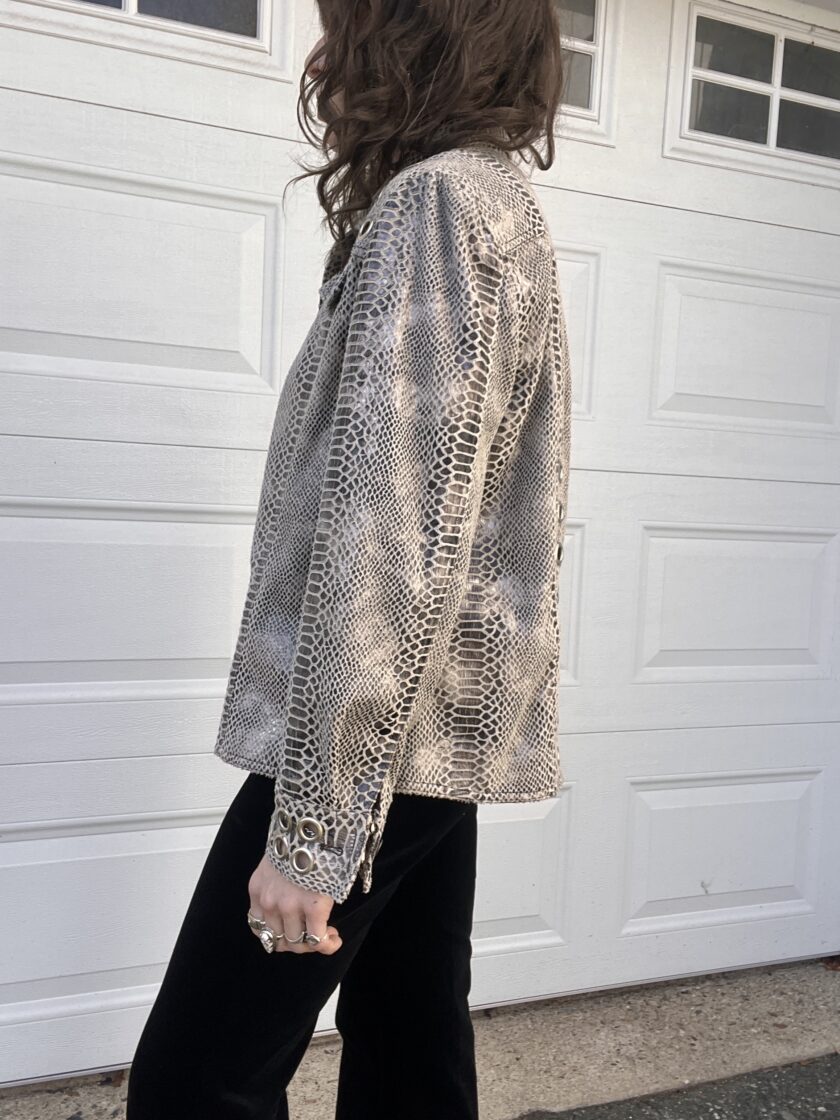 A person wearing a metallic mesh jacket standing in front of a white garage door.