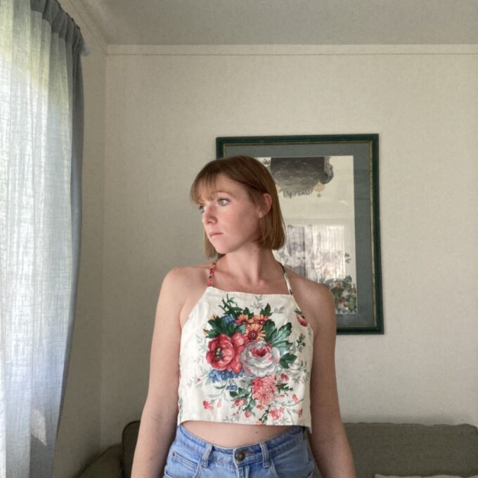 A woman standing in a living room wearing a floral top.