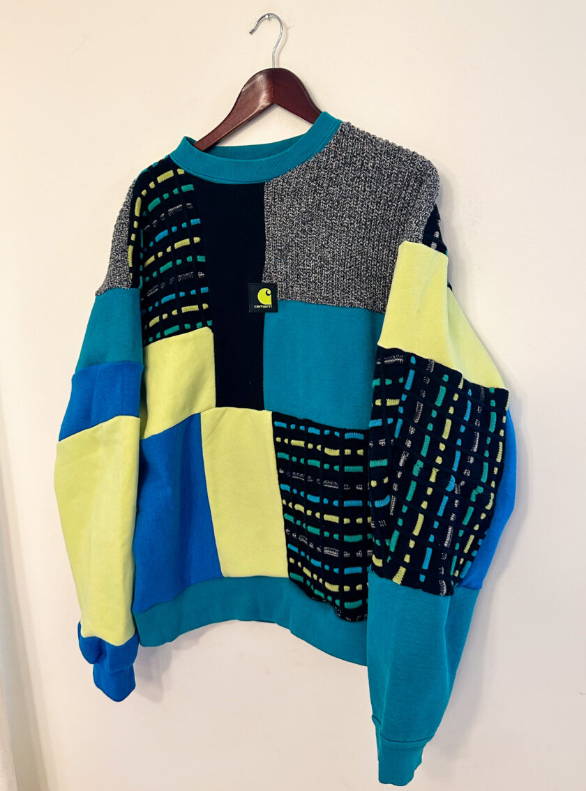 A blue, yellow, and blue sweater hanging on a wall.