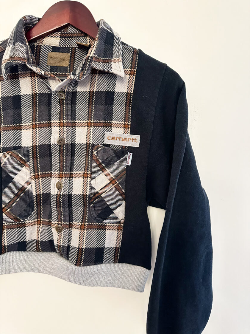 A black and brown plaid shirt hanging on a hanger.