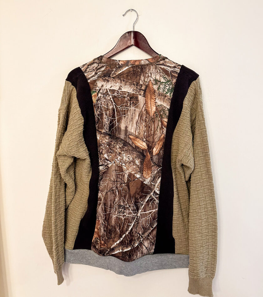 A camouflage sweater hanging on a wall.