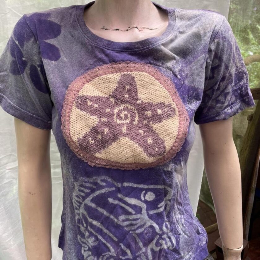 A mannequin wearing a purple t - shirt with a starfish on it.