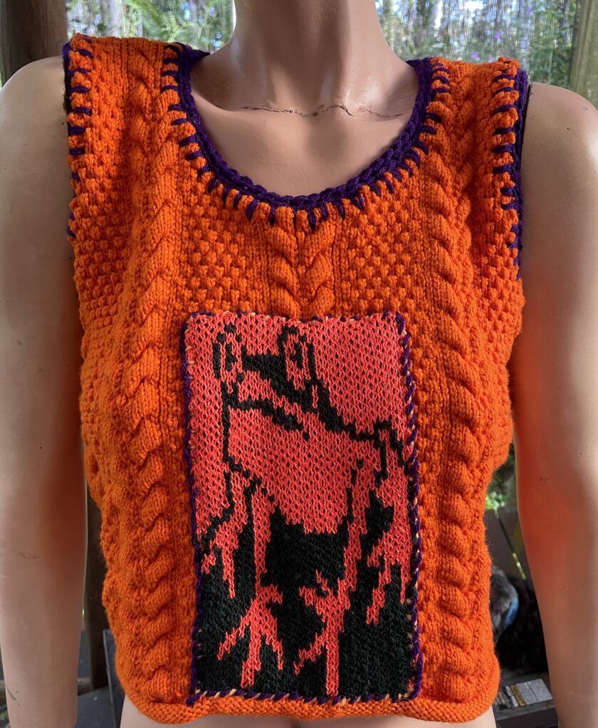 A bright orange knitted vest with a frog