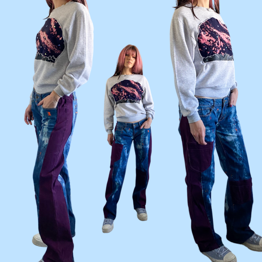 A woman is posing in a pair of jeans and a sweatshirt.