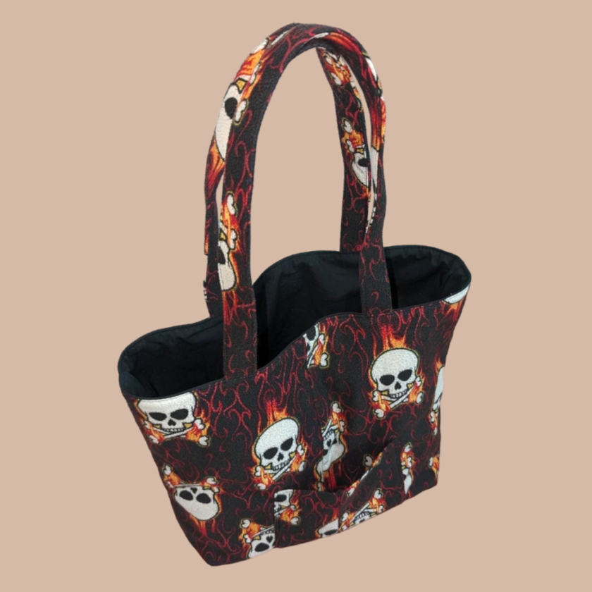 A tote bag with skulls and flames on it.