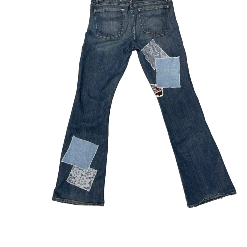 A pair of blue jeans with patchwork on a white background.