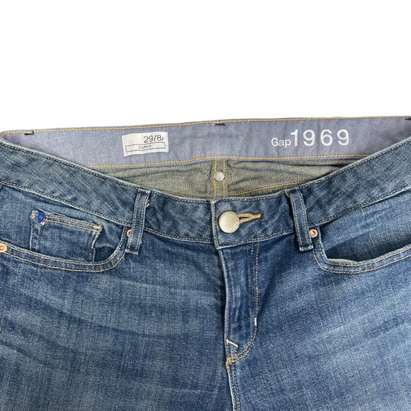 Close-up of a pair of gap 1969 denim jeans displaying the size label, button, and front pocket details.