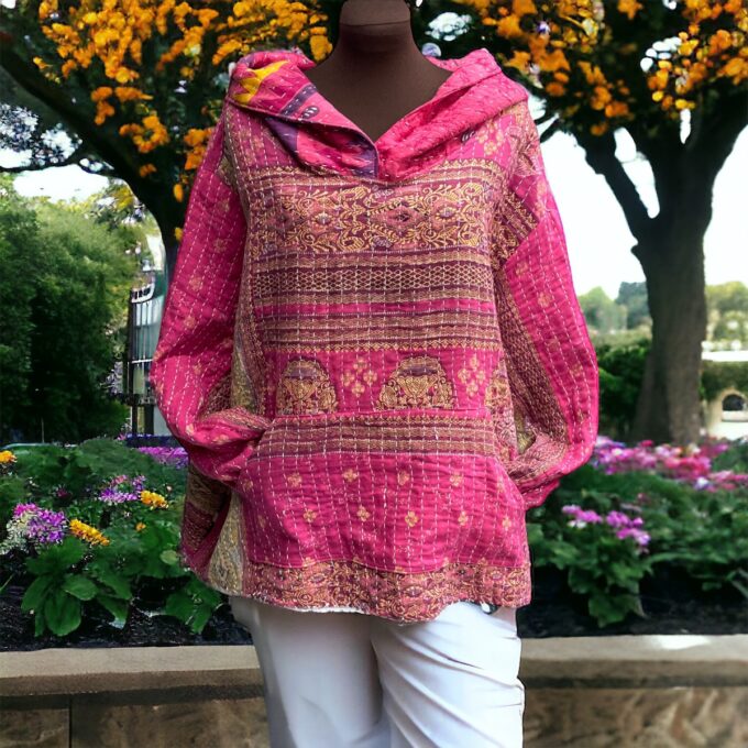 Mannequin displaying a pink patterned hoodie in a garden setting.