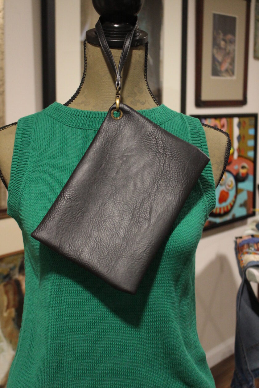 Mannequin displaying a green sleeveless top and a black leather sling bag.