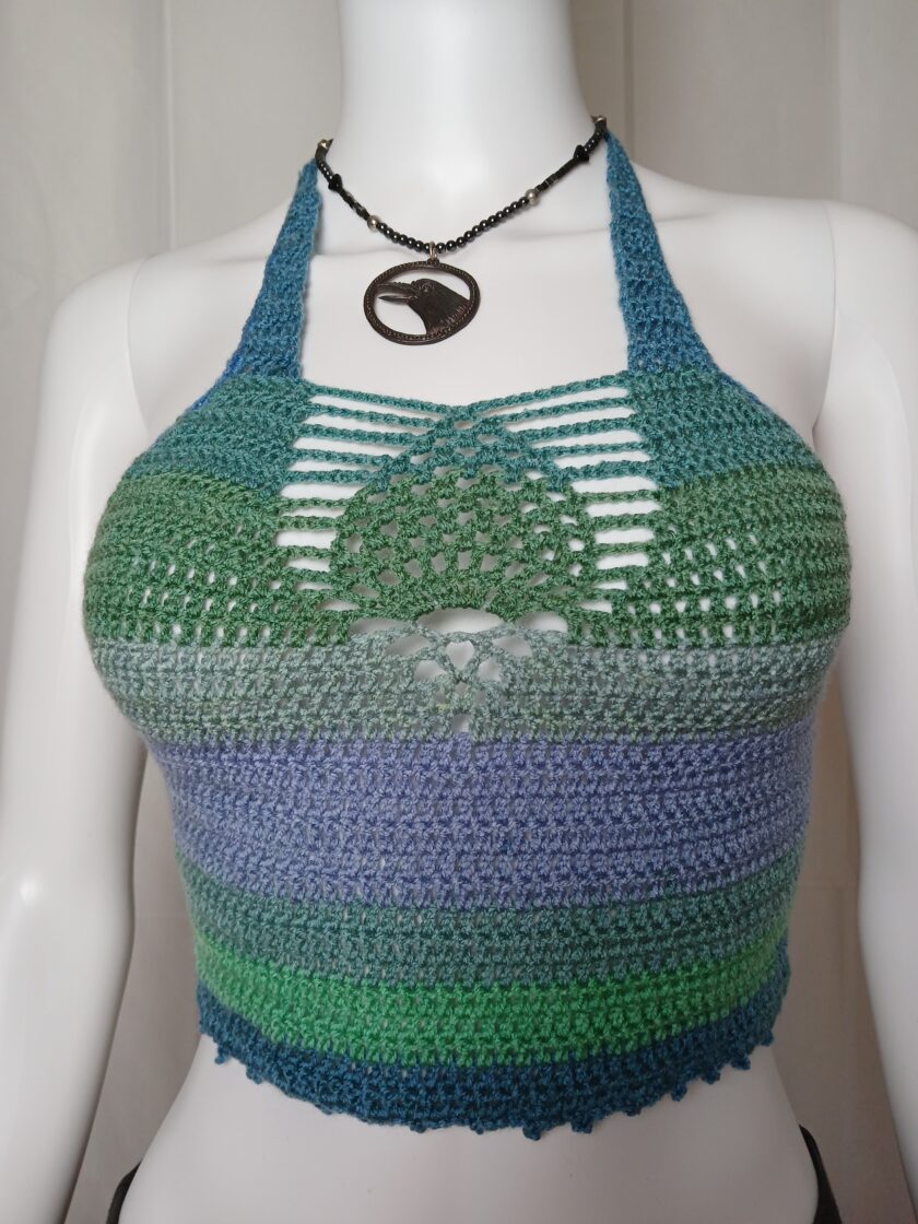 A purple and green crocheted top on a mannequin.