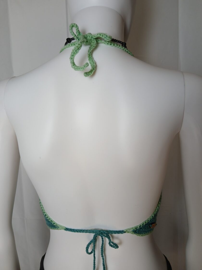 The back of a mannequin wearing a green halter.