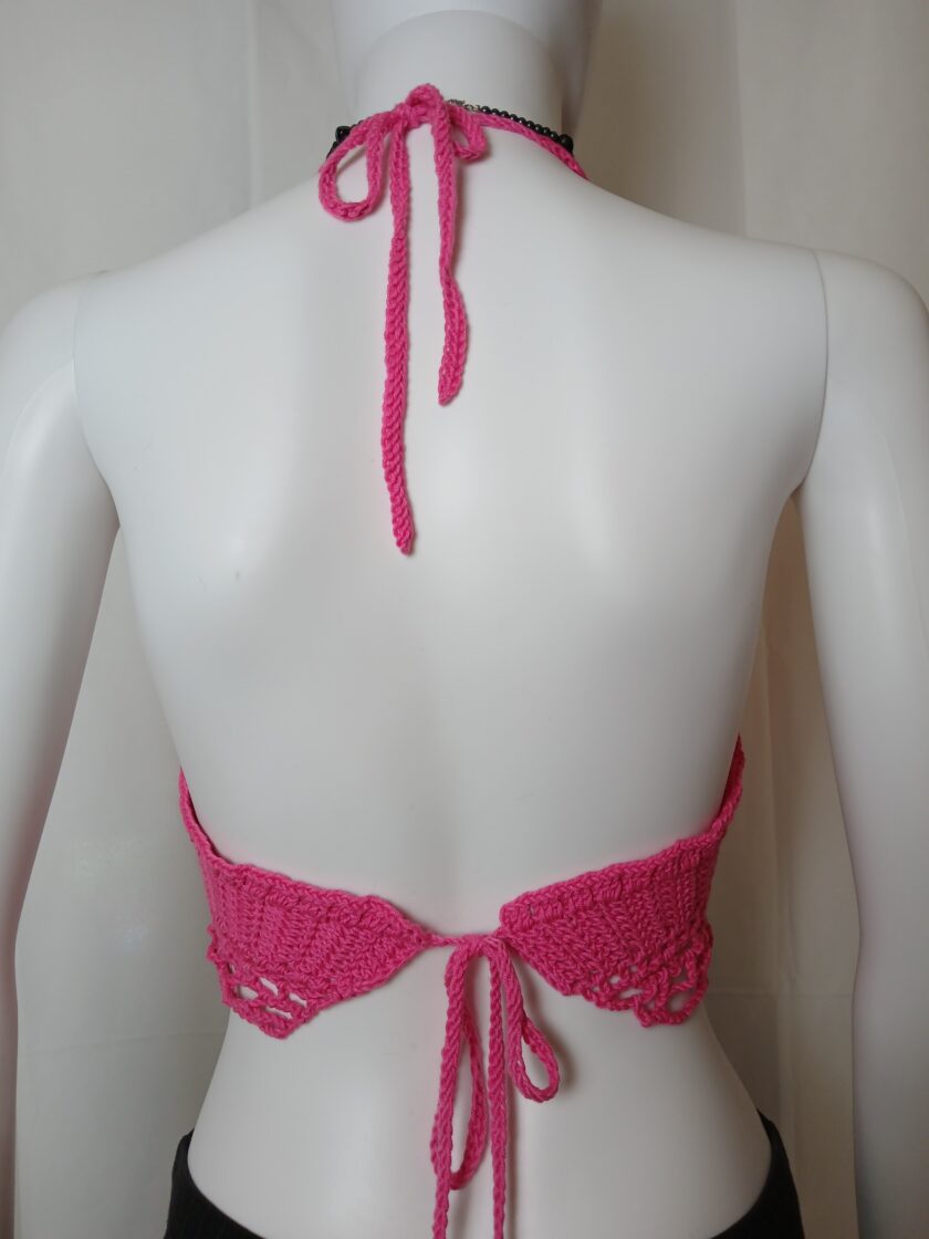 The back of a mannequin wearing a pink crocheted halter top.