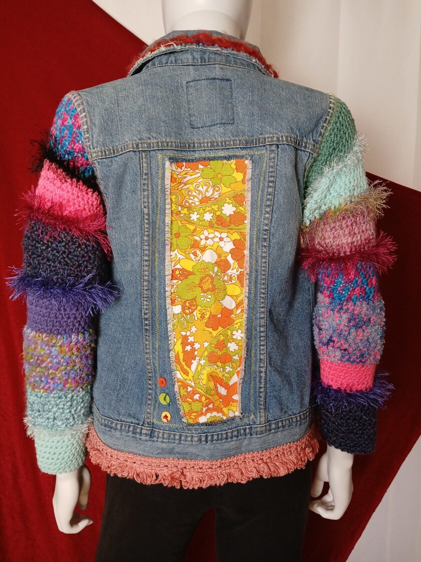 Hippie refashioned denim jacket with colorful 1970s fabric, crochet sleeves and bright buttons