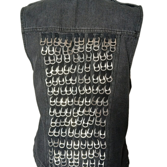 A denim vest adorned with numerous silver-colored pull tabs creating a pattern on the back.