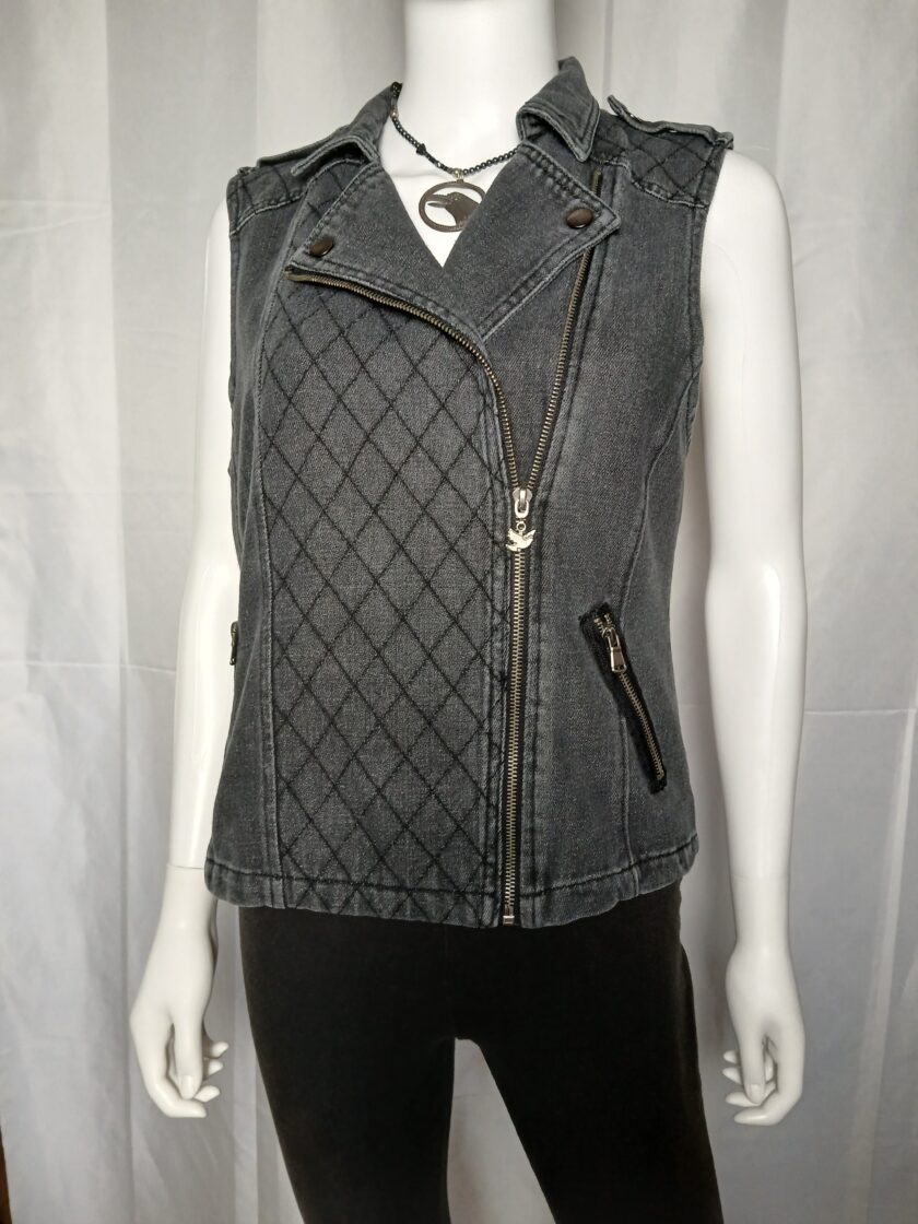 Black denim moto vest with quilted details and zippers displayed on a mannequin.
