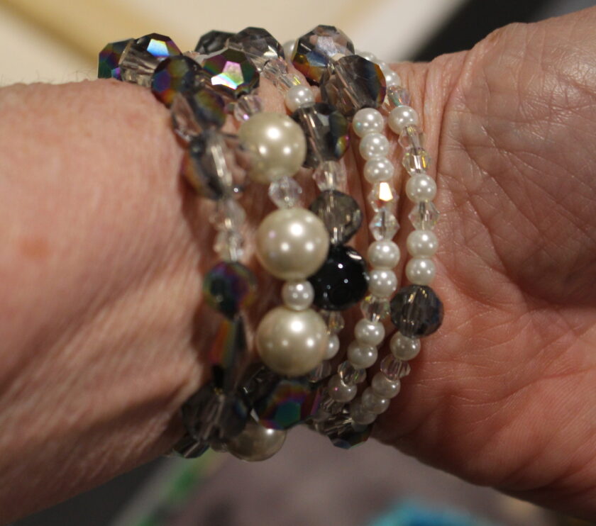 A close-up of a hand wearing multiple beaded bracelets with various designs.