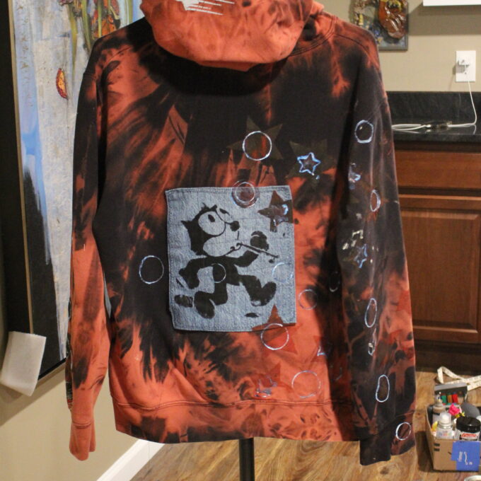 A printed hoodie with a graphic design on display in an indoor setting.