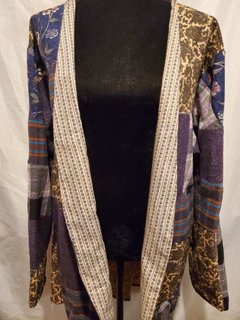A patterned kimono with a mix of floral and paisley designs displayed on a mannequin.