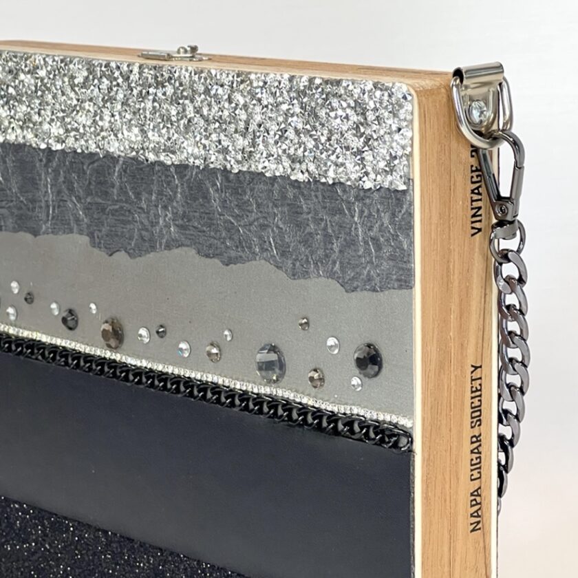 Close-up of a stylish clutch with silver and black glitter bands, and rhinestone embellishments.