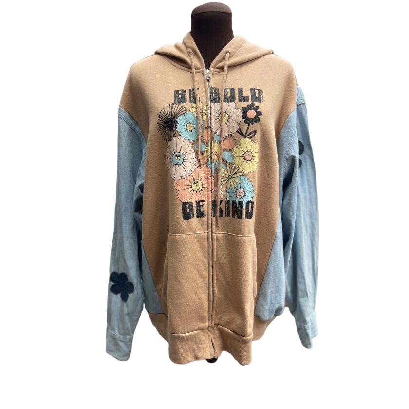 A beige and blue hooded sweatshirt with floral designs and the words "behold beyond" displayed on a mannequin.