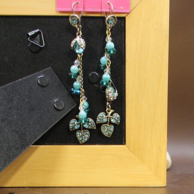 Turquoise beaded earrings with clover-shaped pendants displayed on a stand.