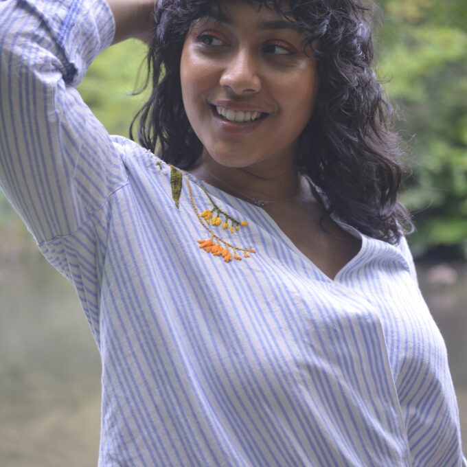 Pochoir.NYC blue and white striped linen wrap top embroidered with flowers at both shoulders.