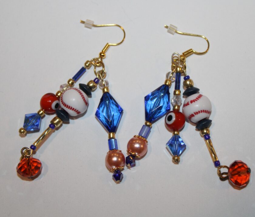 blue pierced dangle earrings with little baseballs, blue crystals and orange pearls and glass beads in three strands.