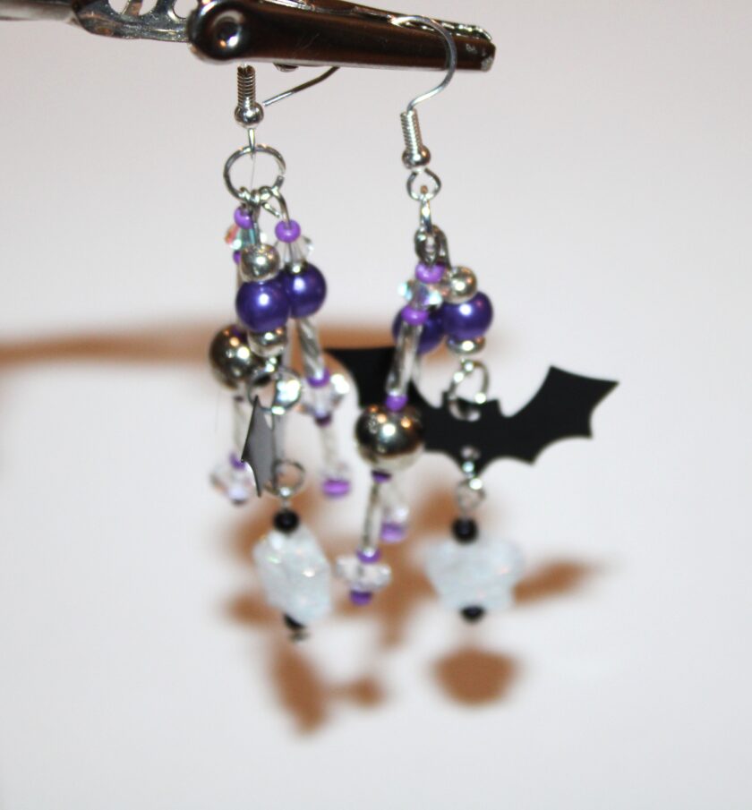 pierced earrings in silver tone with a little black bat and three dangles with purple pearls and purple glass beads